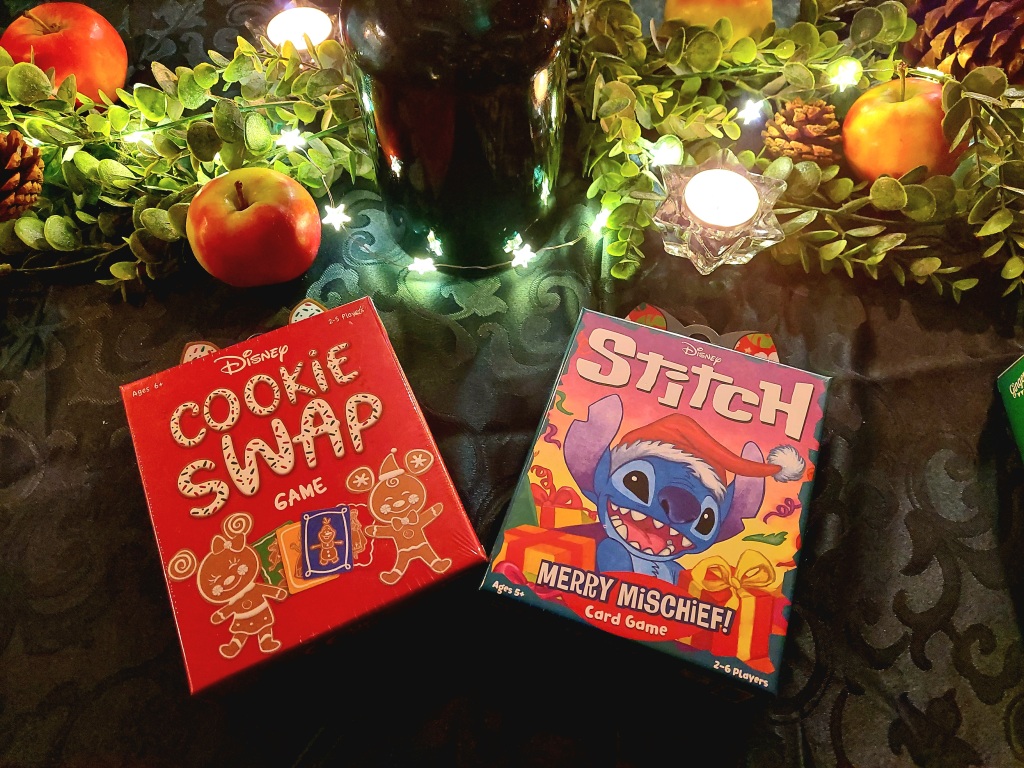 Twee kerstspellen op een versierde tafel met lichtjes en appels. 