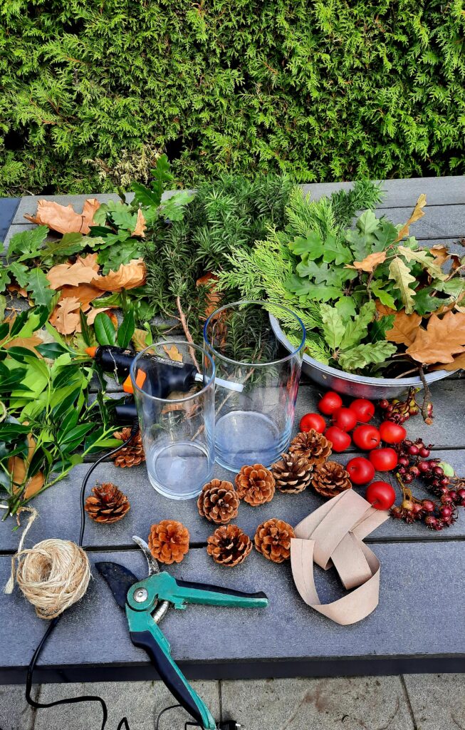 Materialen voor DIY herfst- en kersttafelstuk met natuurlijke elementen en twee vazen. 
