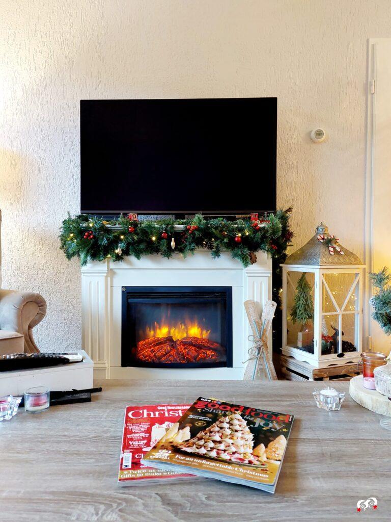 open haard met kerstguirlande en tijdschriften