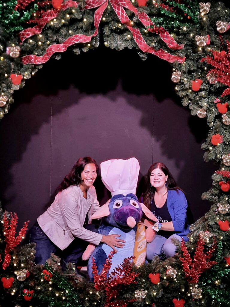 Carmen en Yardéna poseren met een Ratatouille pop onder een feestelijke kerstboog vol decoratie bij Intratuin Halsteren.