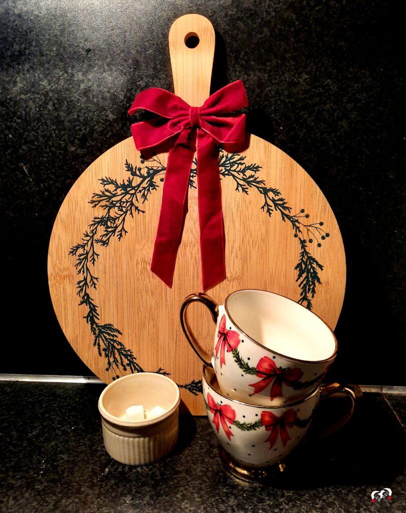 Kerstplank met een rode burgundy strik en twee kerstmokken ervoor