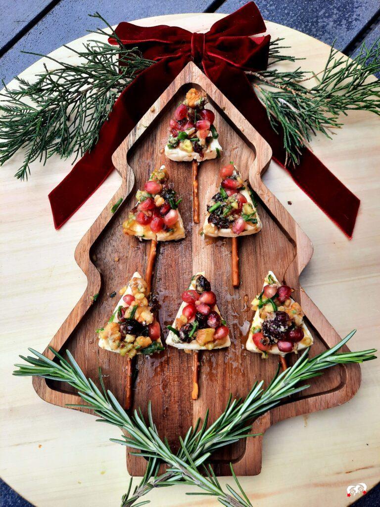 Kerstboom kaaspuntjes op een kerstboom dienblad met rozemarijntakken en een rode strik. 