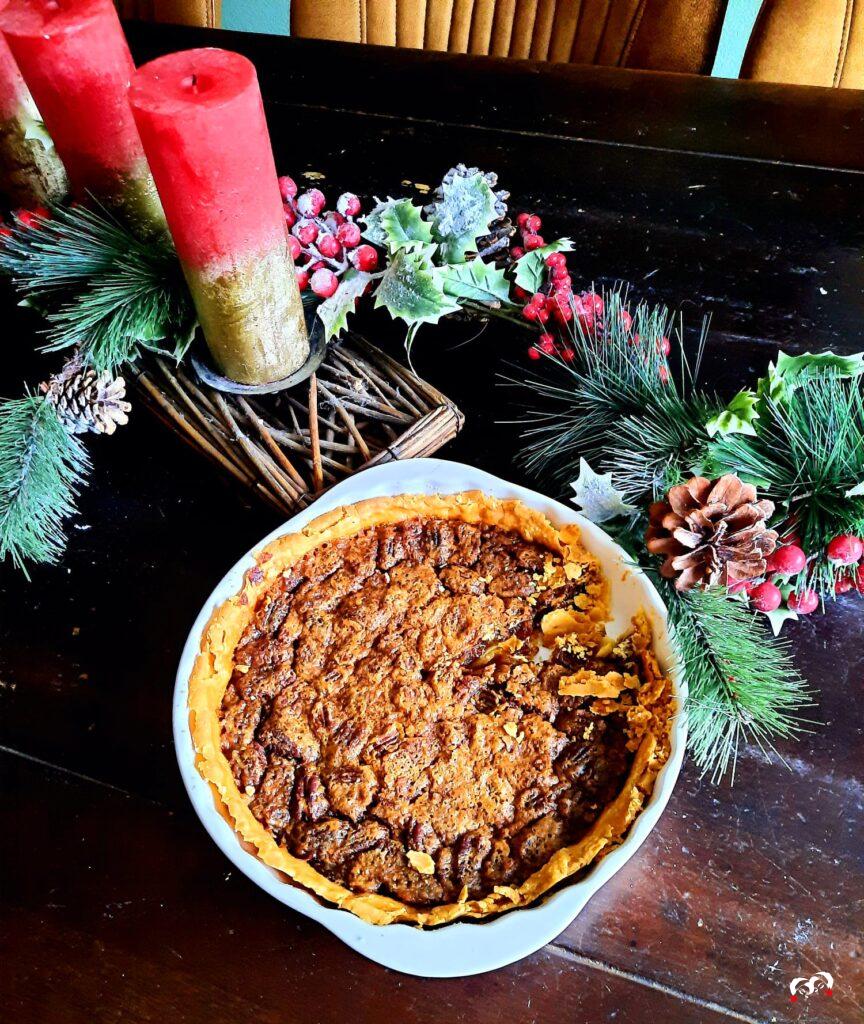 Een Pecan Pie op een donkere tafel met rode kerstversiering