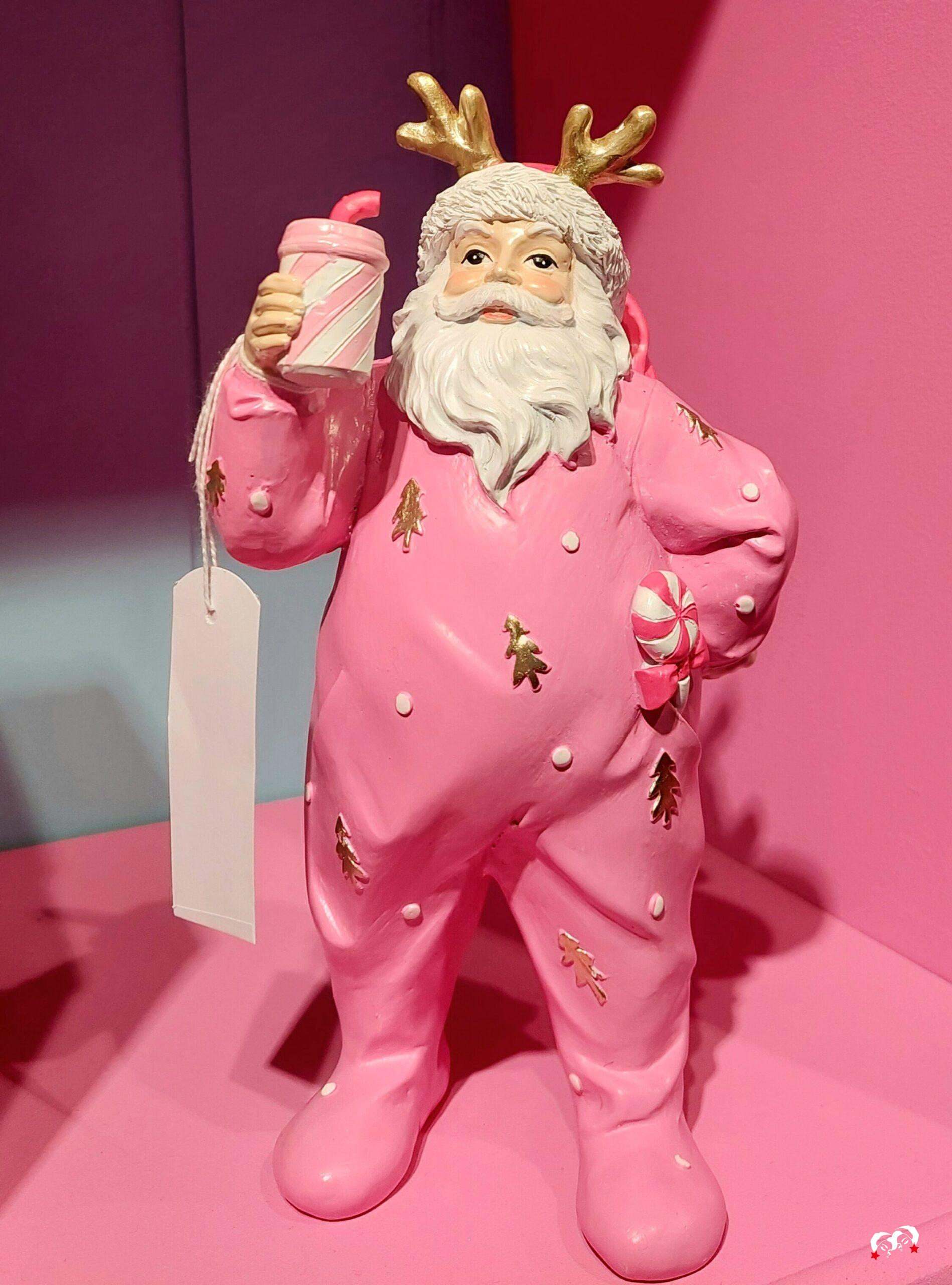 Goodwill Belgium Santa in een roze kerstonesie, omringd door feestelijke kerstsfeer.