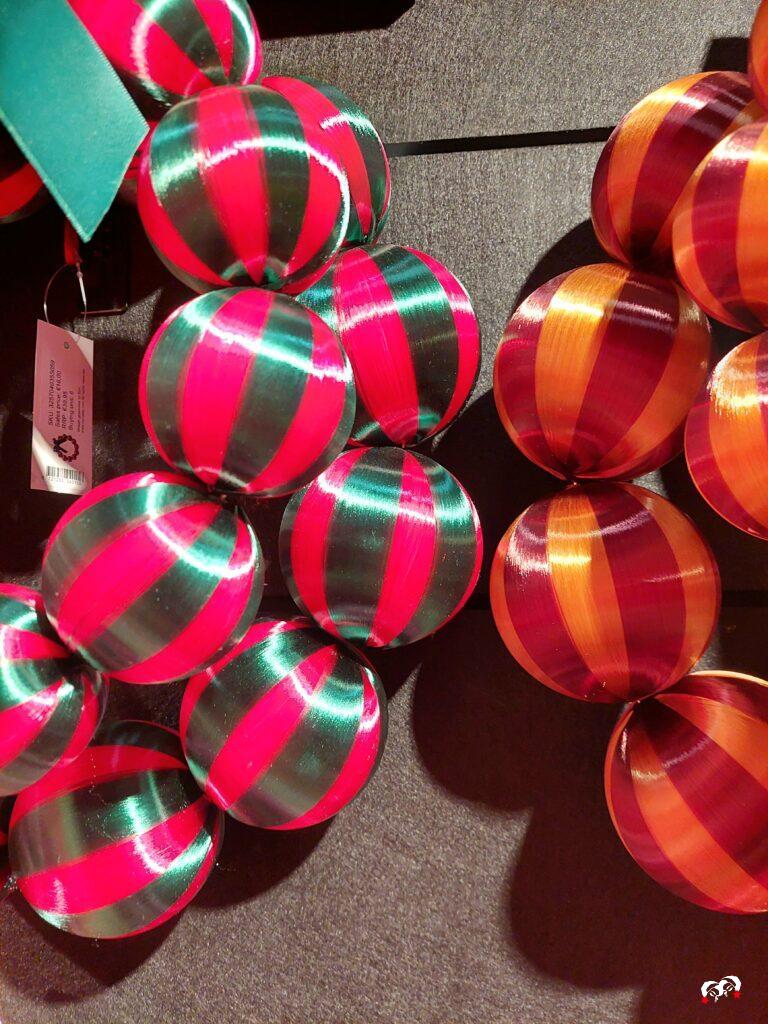 Twee kleurrijke kerstkransen naast elkaar, één met roze en groene kerstballen en één met rode en oranje kerstballen. Bold and expressive