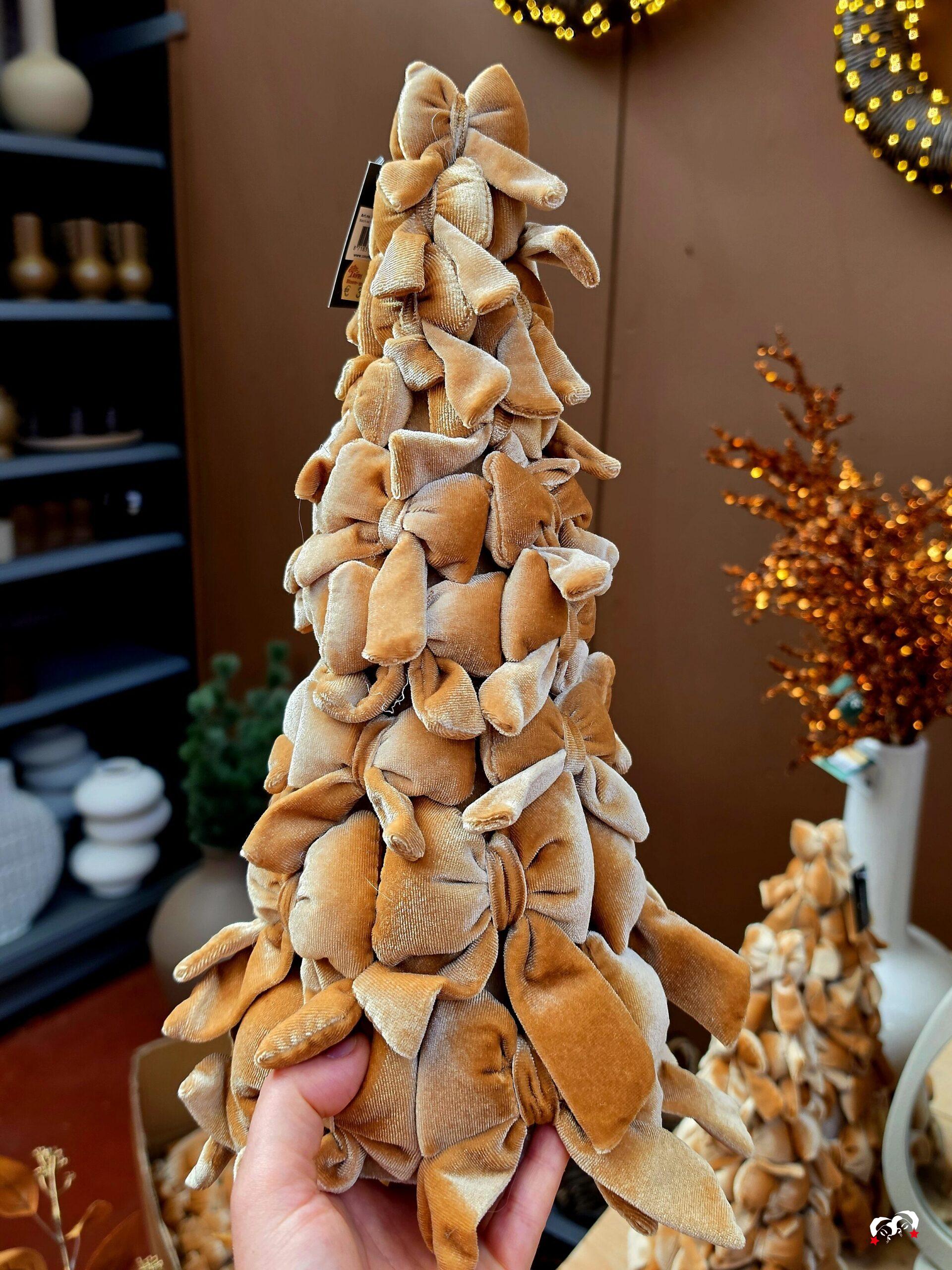 Kerstboom gemaakt van karamelkleurige strikken in een hand