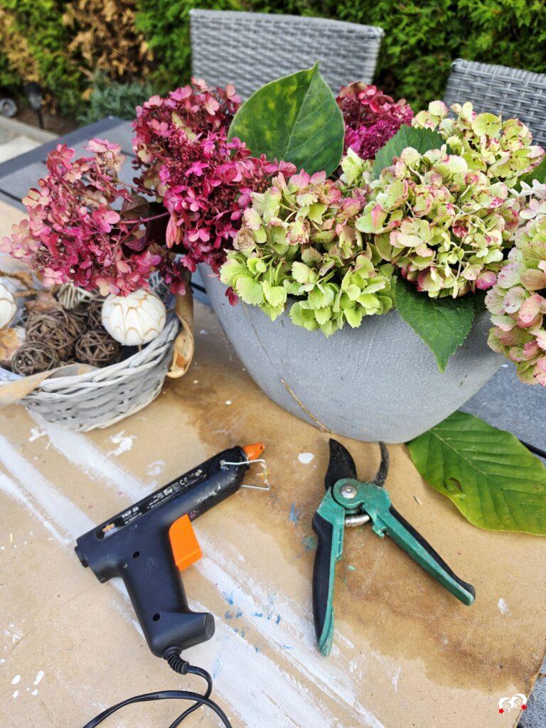 Hortensia’s drogen in een vaas met een lijmpistool en schaar voor een DIY herfst tafelstuk