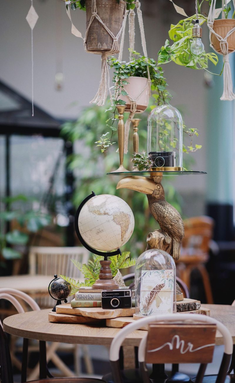 Tafeldecoratie met wereldbollen, vintage camera en planten in urban jungle setting
